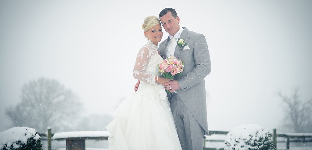 The happy couple steal a moment in the snow covered Walled Garden at Gaynes Park