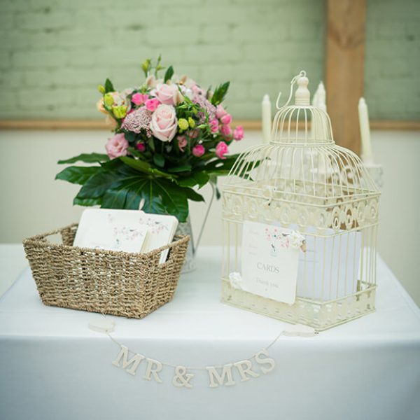 A wicker basket and whit birdcage for wedding cards beautifully reflects the couple’s vintage wedding theme
