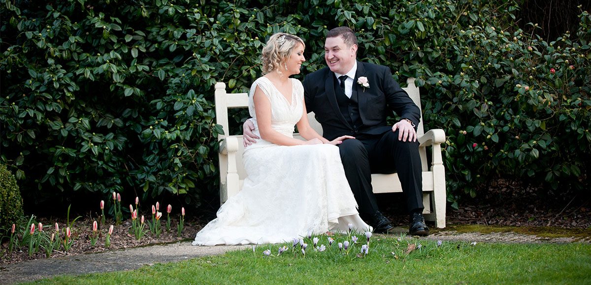 Bride and groom relaxing outside on a bench – barn wedding venues