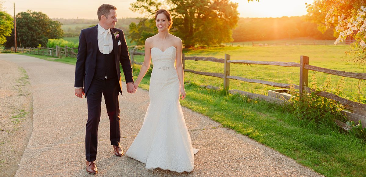 Bride and groom enjoying the sunset over the fields of Gaynes Park