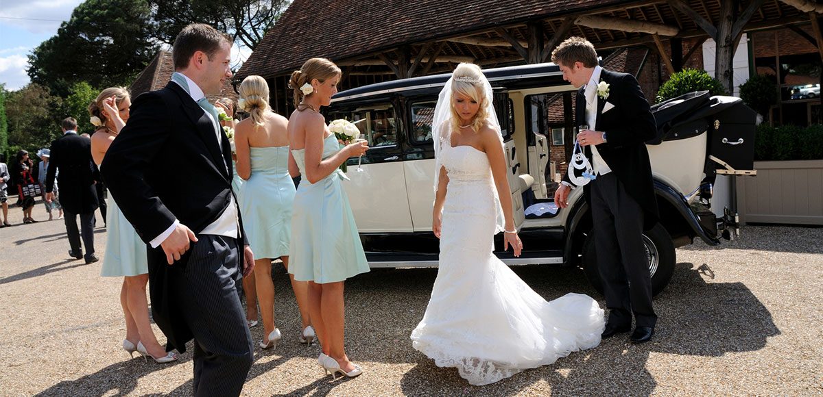 Bride and groom by their wedding transport – barn hire Essex
