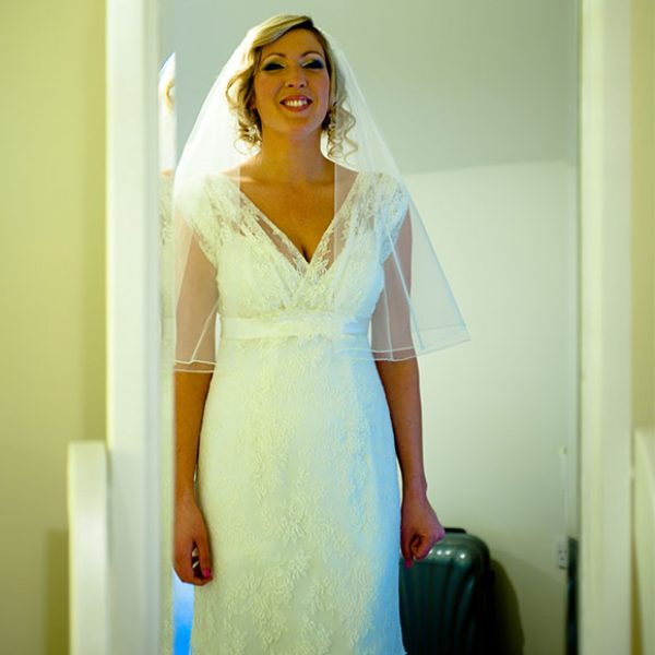Bride looking at her dress in the mirror just before her wedding ceremony at Gaynes Park