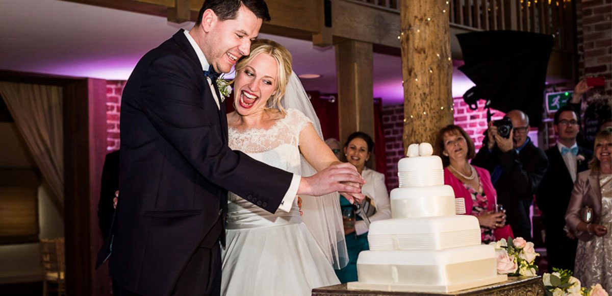 Bride and groom cutting the cake at Gaynes Park – barn wedding venues