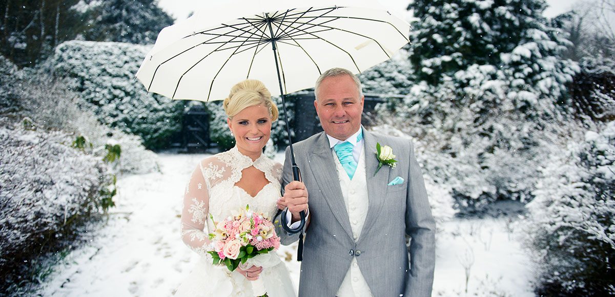 Father of the bride and bride in the snowy garden