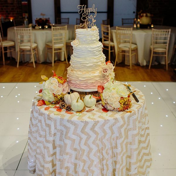 A magnificent ombre wedding cake covered in blush and cream iced ruffles with iced rose features