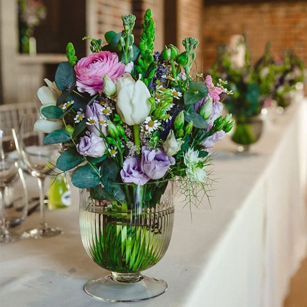 Flowers in a glass urn to decorate tables at Gaynes Park wedding