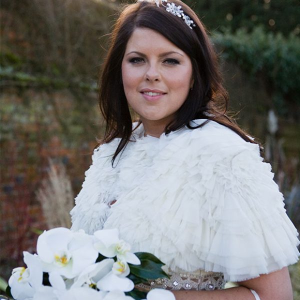 Winter bride with shawl and flowers at her barn wedding reception
