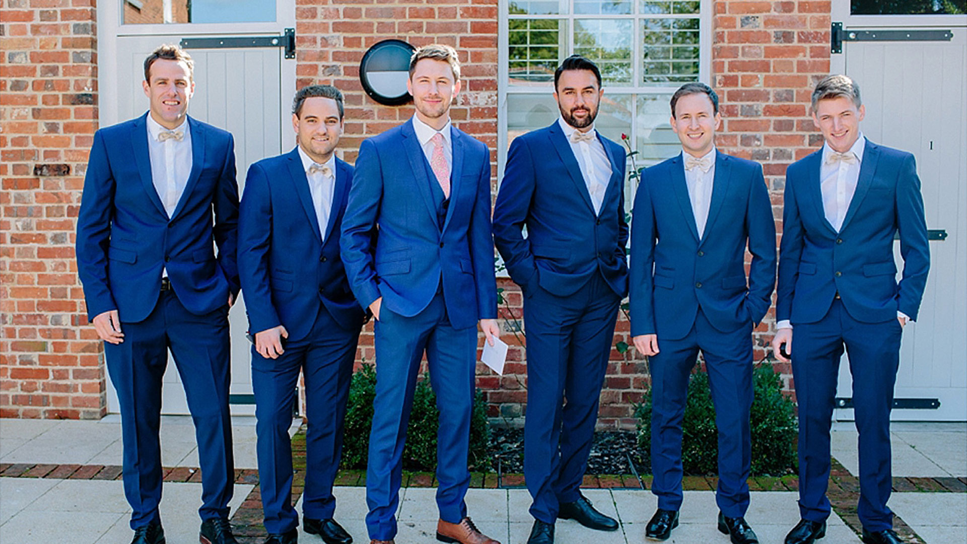 A groom and his groomsmen look stylish in blue suits ready for a barn wedding