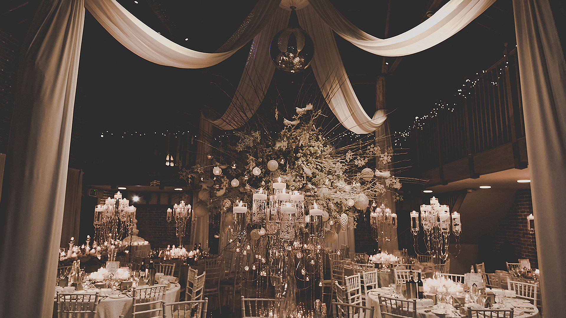The Mill Barn is decorated with white drapes and candelabras for a beautiful winter wedding