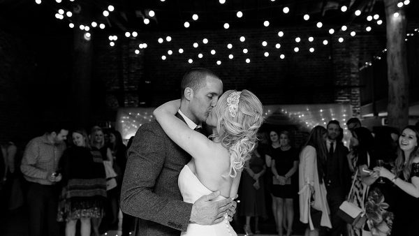 A happy couple steal a kiss on the dancefloor during their evening wedding reception in the Mill Barn