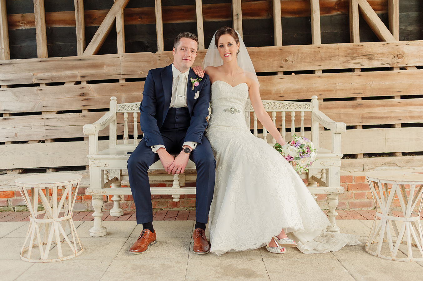 bride-and-groom-sit-on-wedding-bench-gaynes-park