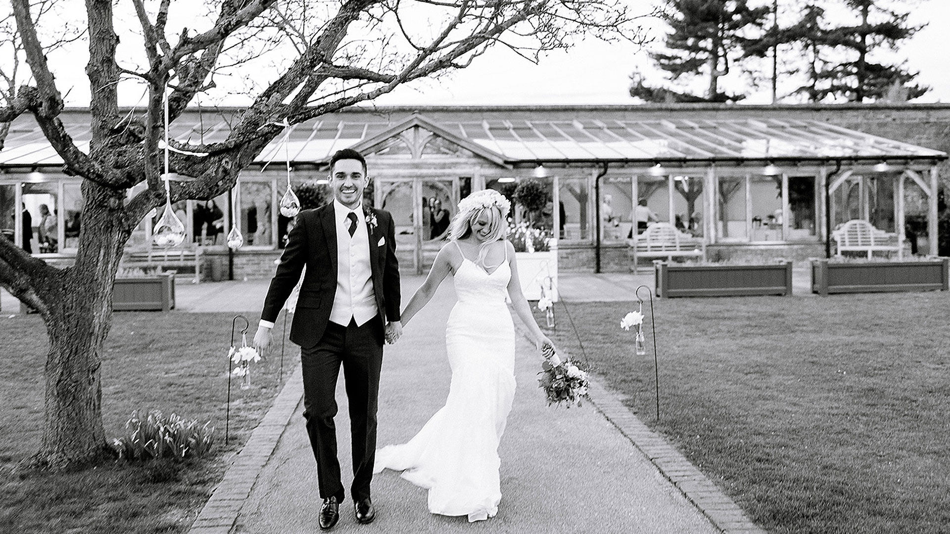 A happy bride and groom walk away from the Orangery after saying their marriage vows in a wedding ceremony