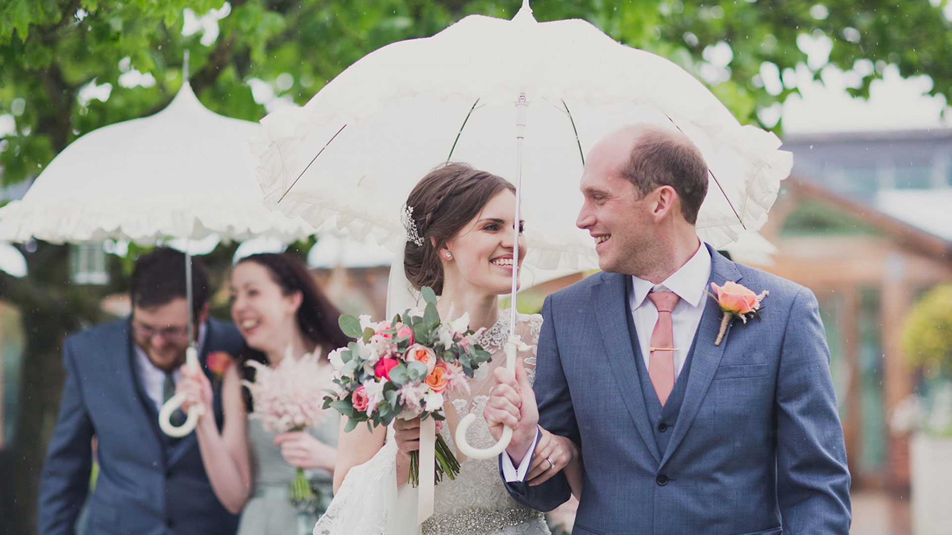 A bride and groom walk together - pink and peach wedding colours are perfect for a summer wedding