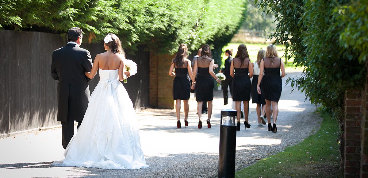 Bride and her father following the bridesmaids to the wedding ceremony at Gaynes Park