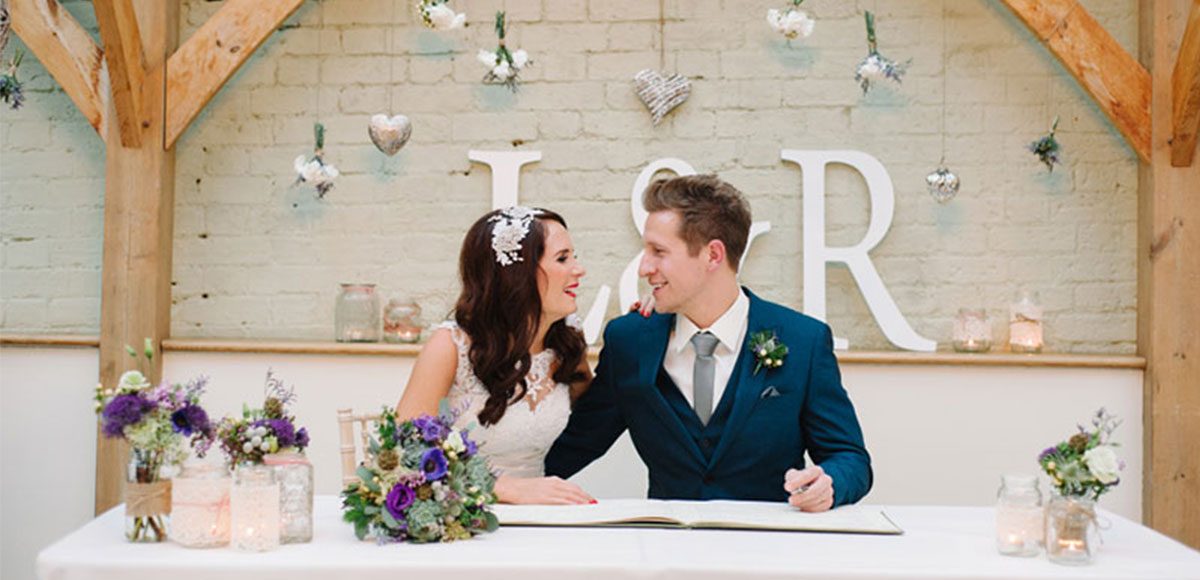Bride and groom sign the register in the Orangery at Gaynes Park – wedding venue in Essex
