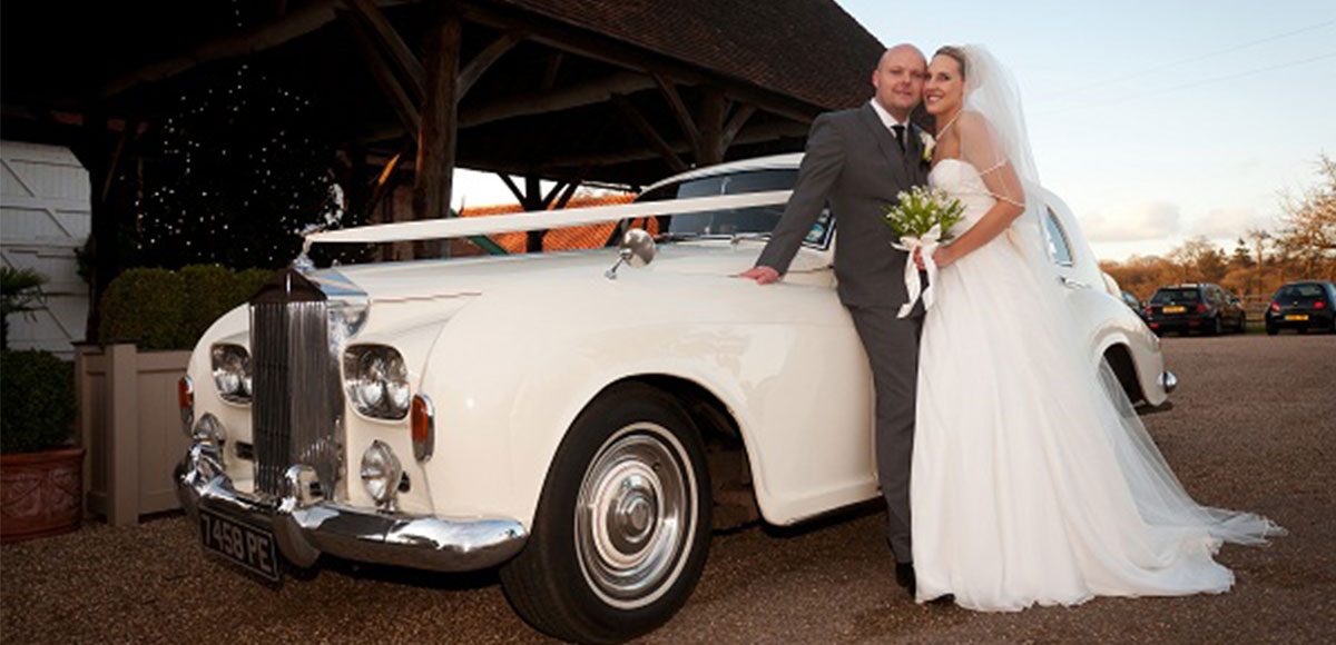 Bride and groom with their vintage wedding transport.