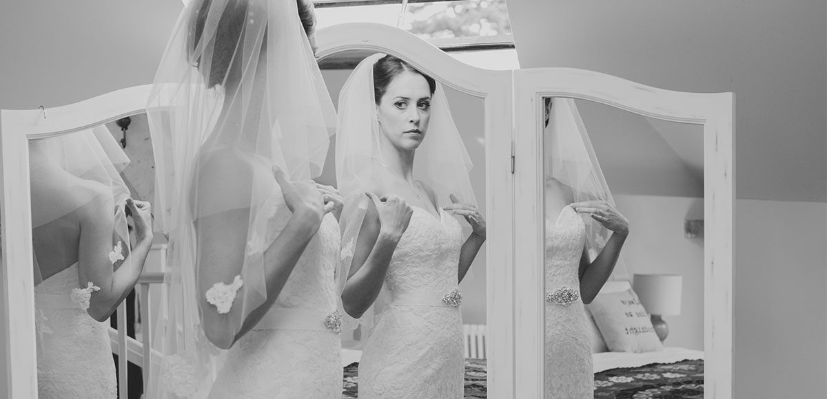 Bride looking in the mirror before her wedding at Gaynes Park