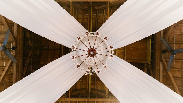 A stunning crystal chandelier hangs from the ceiling in the Mill Barn - wedding decoration ideas