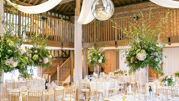 The Mill Barn is decorated with huge flower wedding table centerpieces and drapes from the ceiling