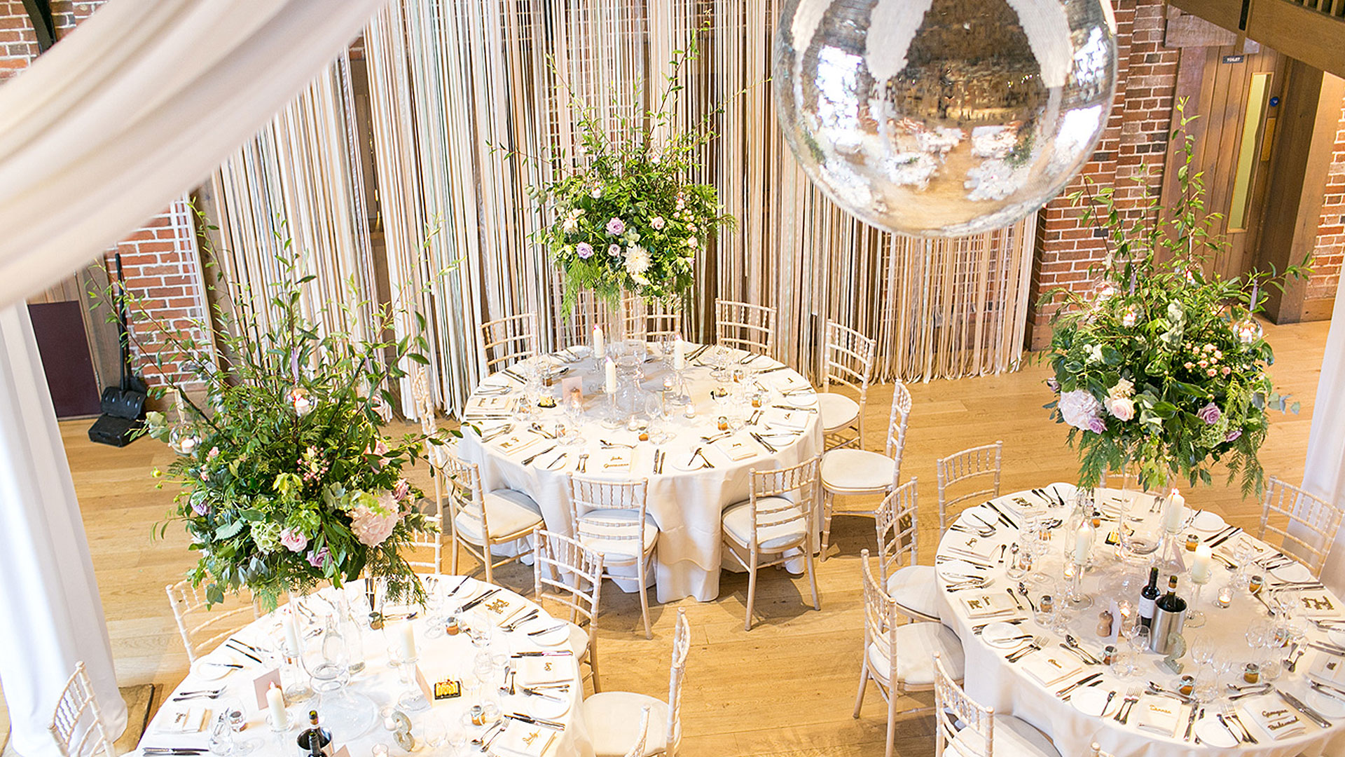 A disco ball hangs from the ceiling in this Essex barn wedding venue - wedding ideas