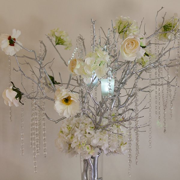 Decorative wood branches painted silver with ivory flowers and crystal decorations