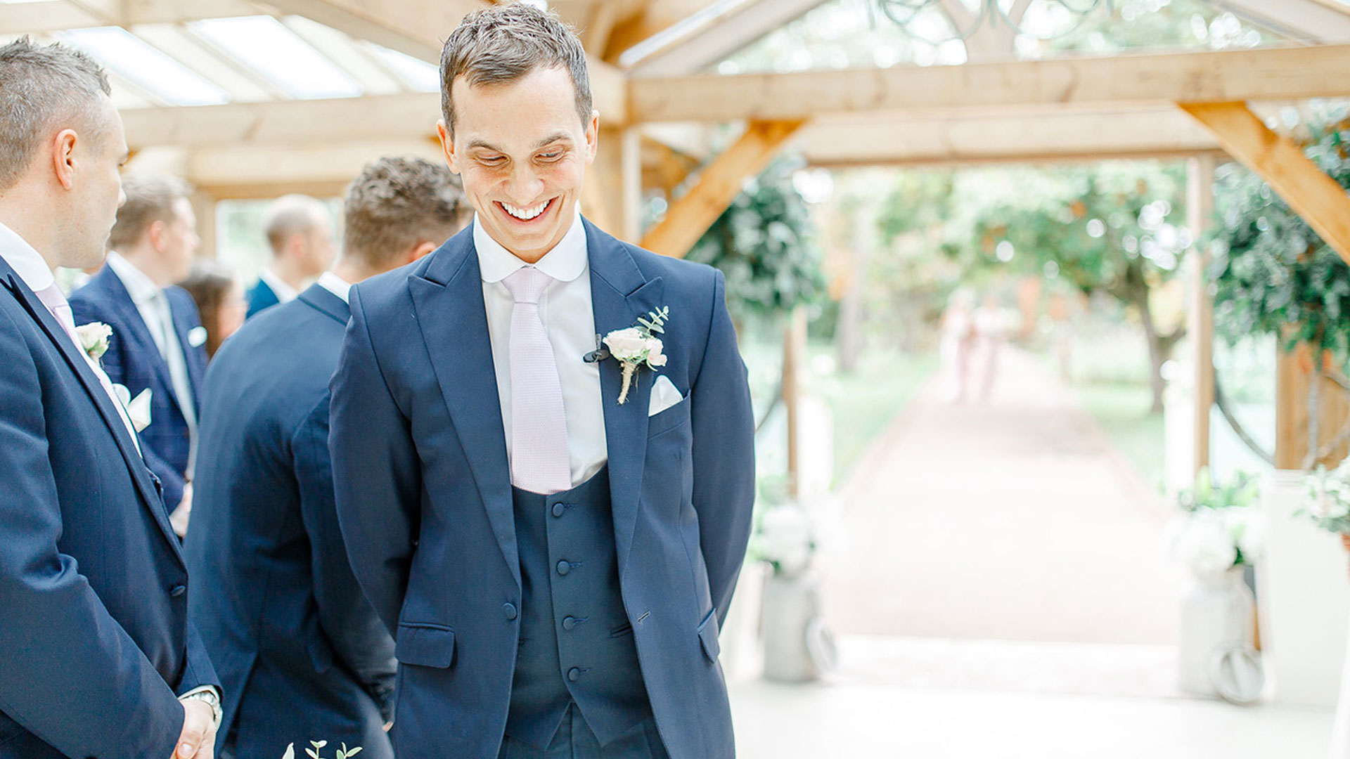 A smiling groom awaits the arrival of his bride in the Orangery - wedding ceremony venues Essex