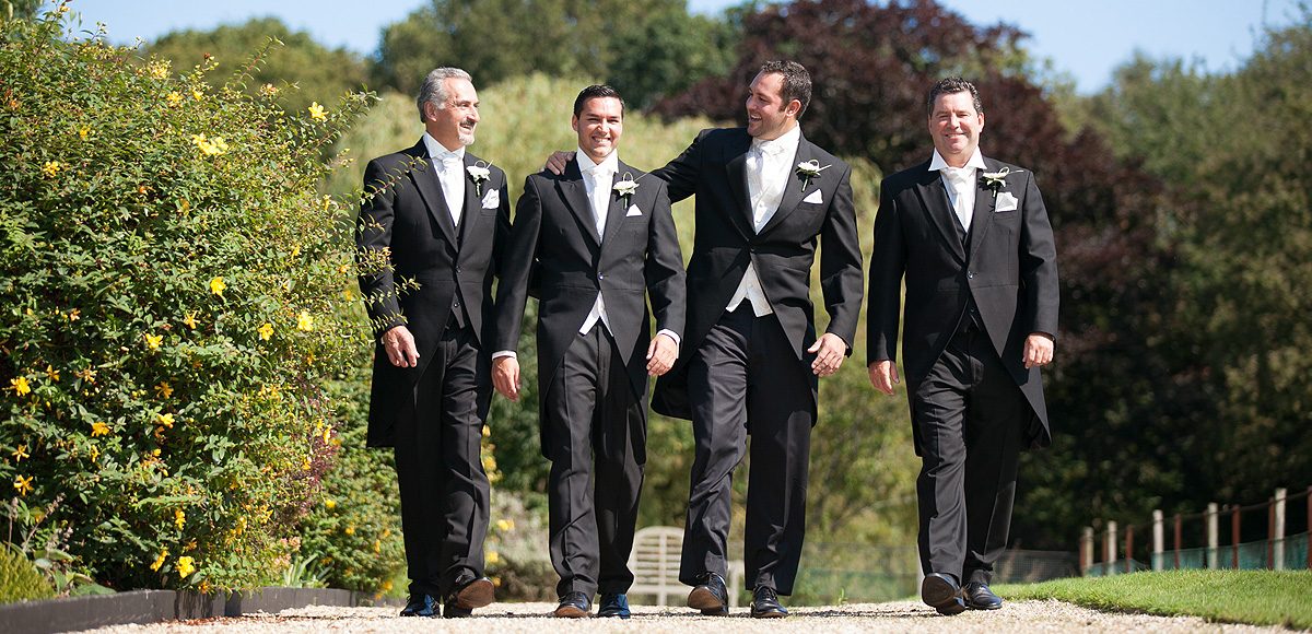 The groom and groomsmen dressed in black tuxedos for a wedding
