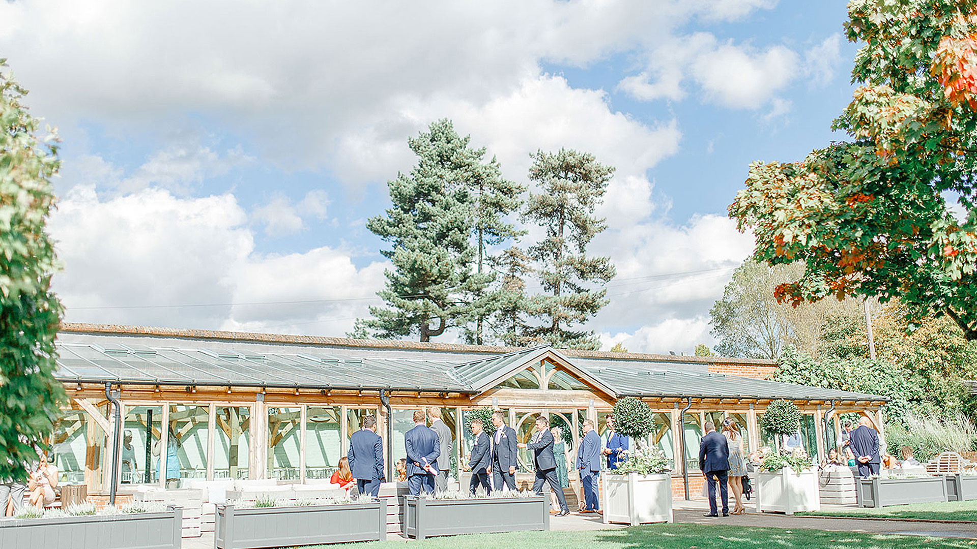 Groomsmen welcome guests to the Orangery ready for the wedding ceremony - barn weddings Essex