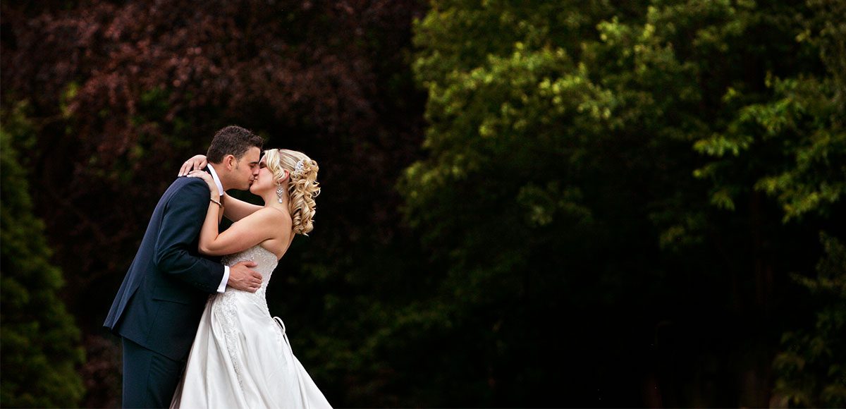 Bride and groom kissing in the gardens at Gaynes Park