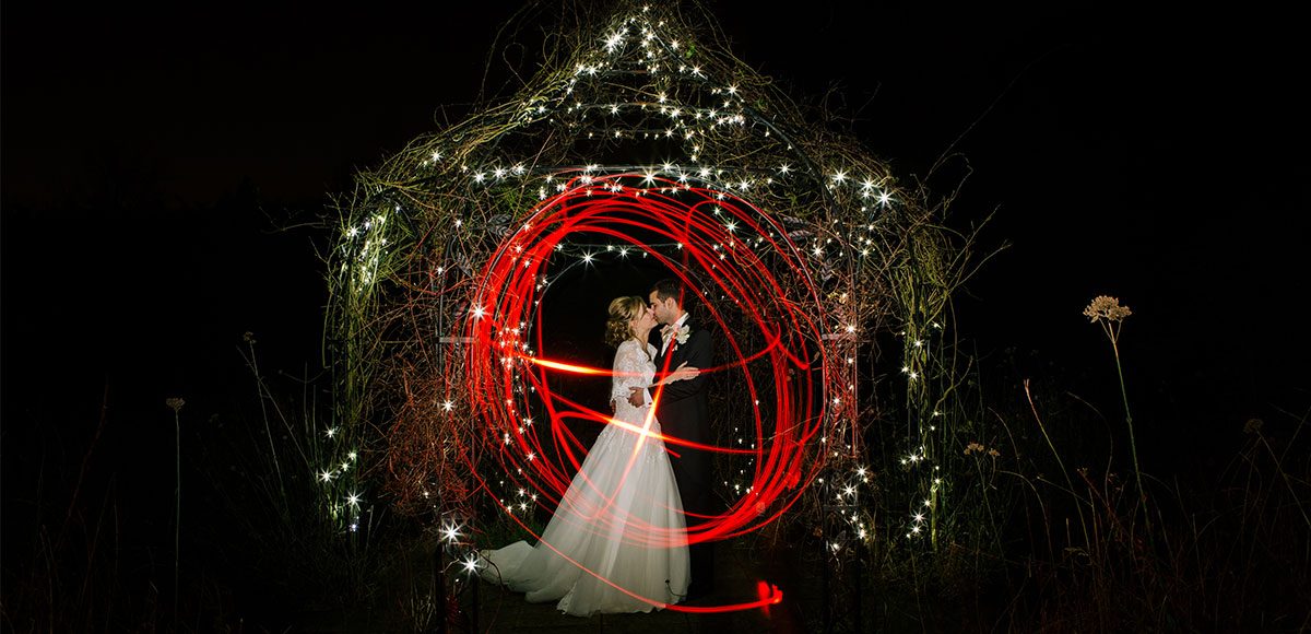 Couple pose for a light trail photo in the gardens at night.