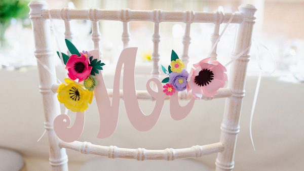 A white wooden chair decorated with colourful paper flowers and Mr wedding sign - wedding decoration ideas