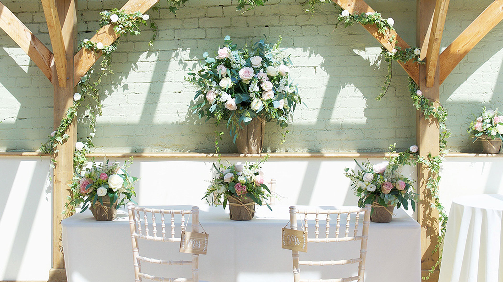 Pale pink and white roses decorate the wedding ceremony table in hessian baskets - rustic wedding ideas