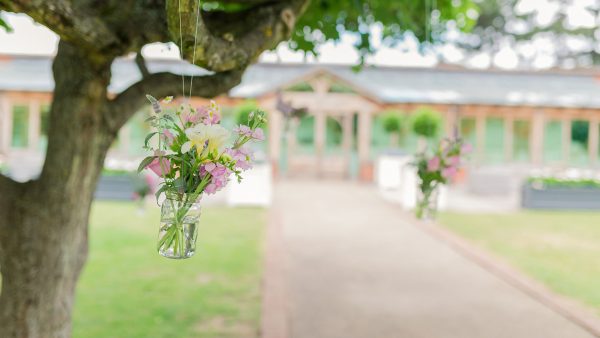 Hanging wedding flowers in clear glass jars from the trees in the Walled Garden is a gorgeous idea for a spring wedding