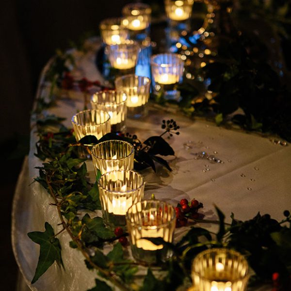 Table decorated with candles and holly for a winter wedding.