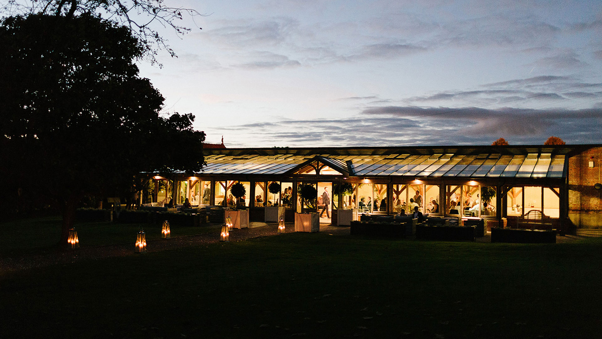 The Orangery looks beautiful at night and the wedding aisle lined with lanterns - ceremony wedding venues in Essex