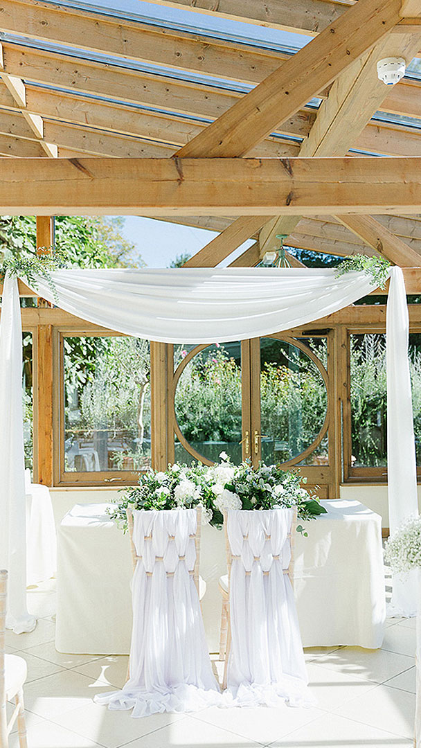 Beautiful white drapes and chair covers decorate the Orangery of this civil wedding venue in Essex