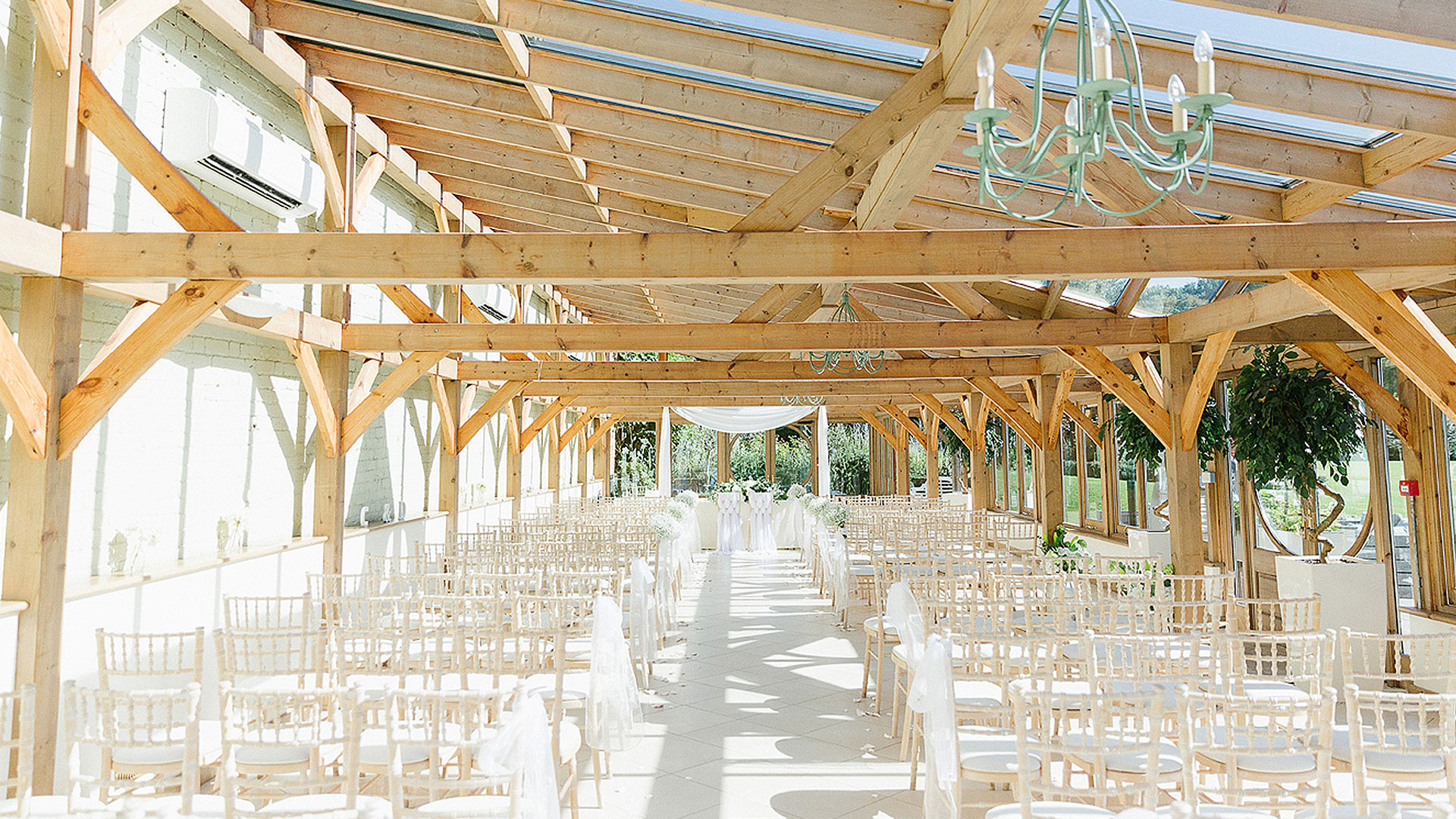 Rows of white wooden chairs line the Orangery ready for a beautiful and unique wedding ceremony