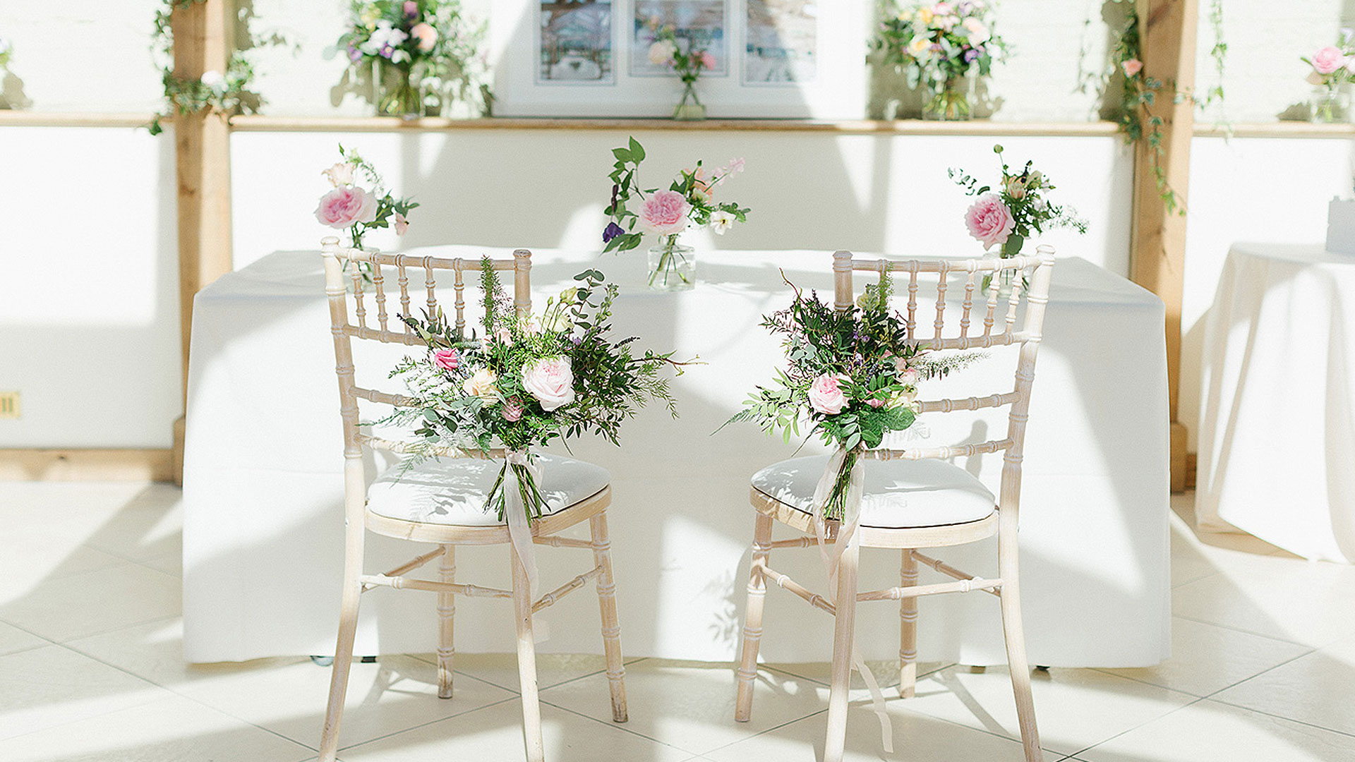 Flowers adorn wooden chairs at this pretty summer wedding at Gaynes Park wedding venue in Esssex