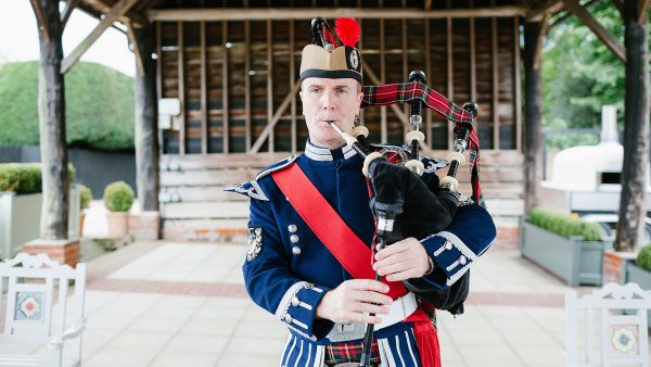 A piper plays the bagpipes for wedding music in the Gather Barn wedding barn