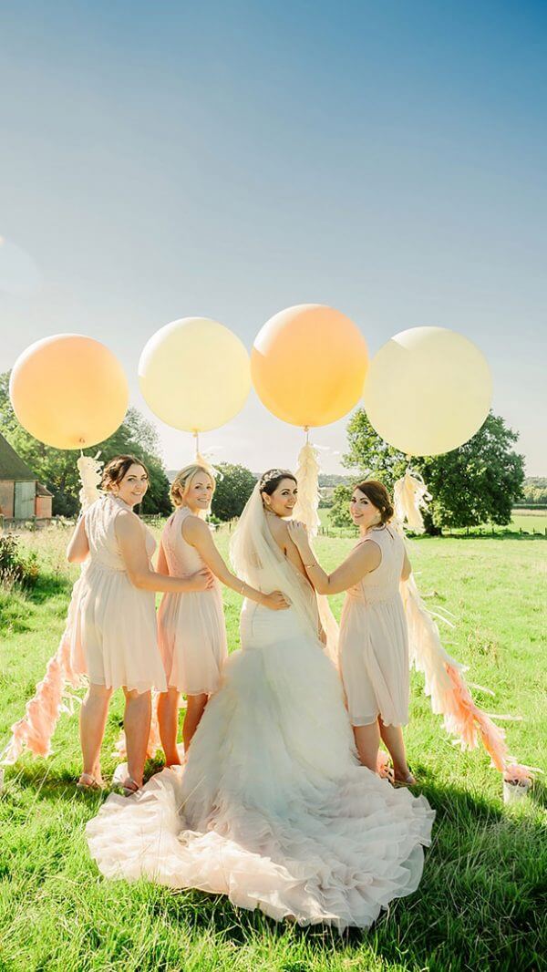 A bride and her bridesmaids enjoy the countryside setting with wedding balloons