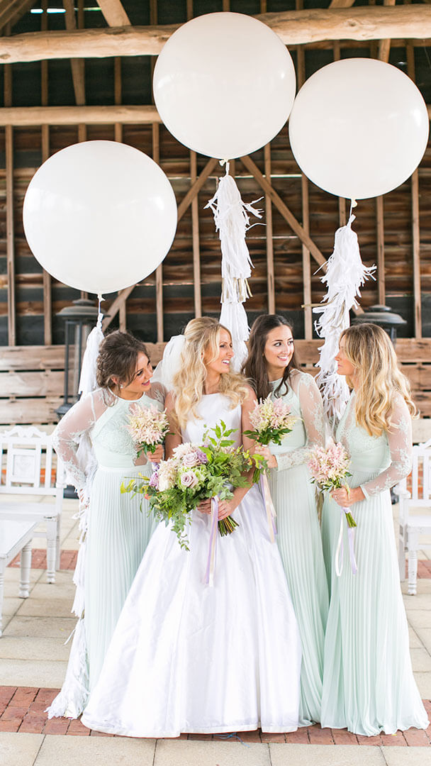 A bride chats with her bridesmaids in the beautiful barn wedding venue - wedding balloon displays
