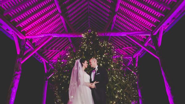 A couple stand in front of a Christmas Tree in the Gather Barn - winter wedding decorations