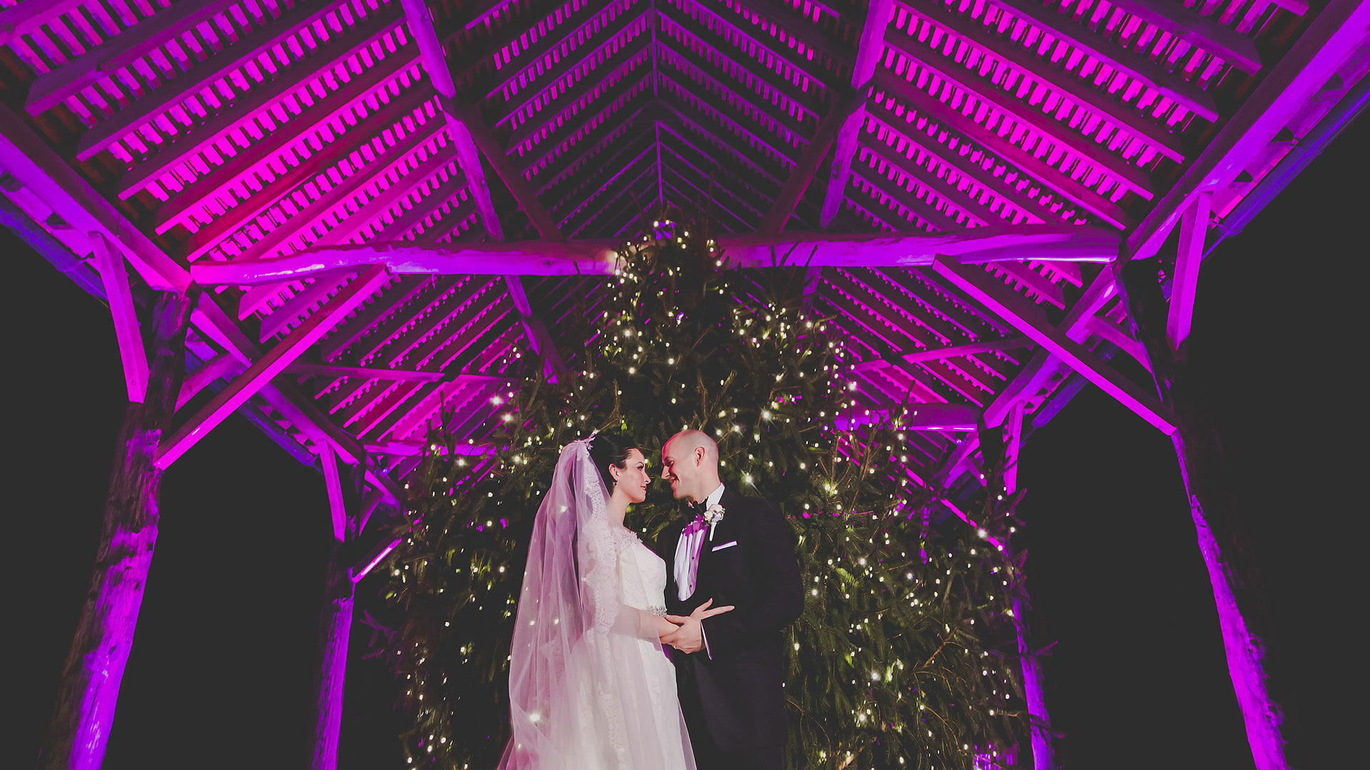 A couple stand in front of a Christmas Tree in the Gather Barn - winter wedding decorations