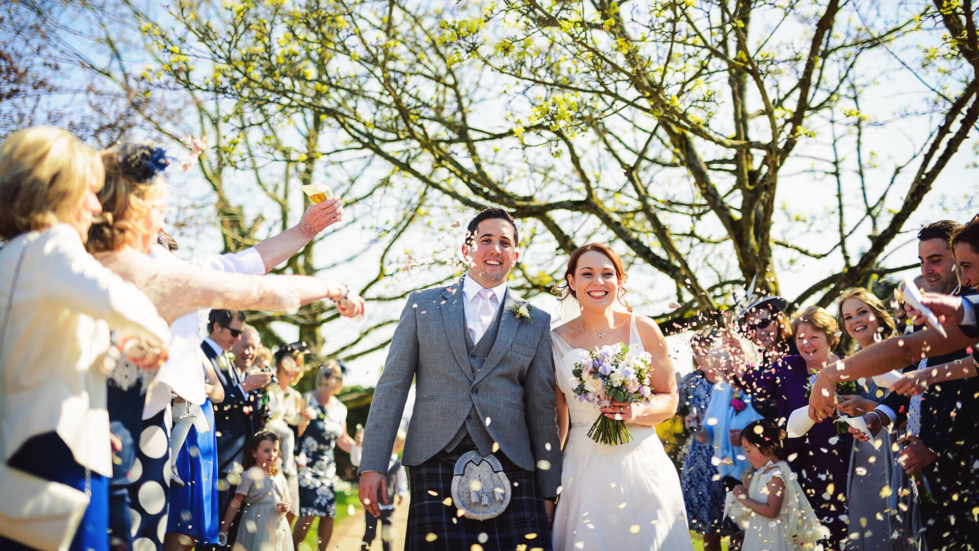 A bride and groom are congratulated with confetti after their wedding ceremony