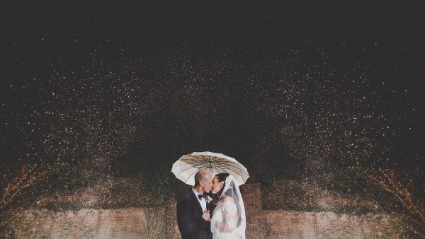 A couple kiss under falling snow at Gaynes Park winter wedding venue in Essex