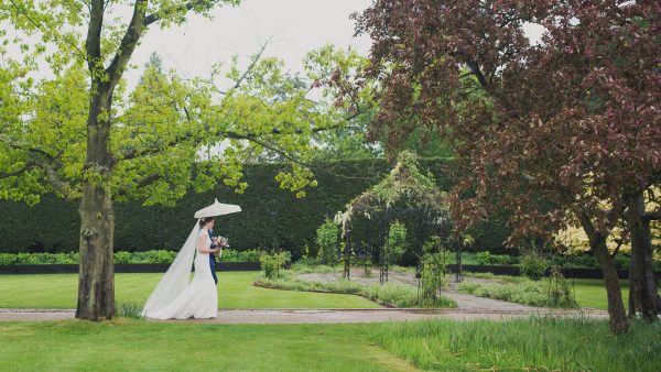 A bride walks down the long outdoor wedding aisle at one of the finest wedding venues in Essex