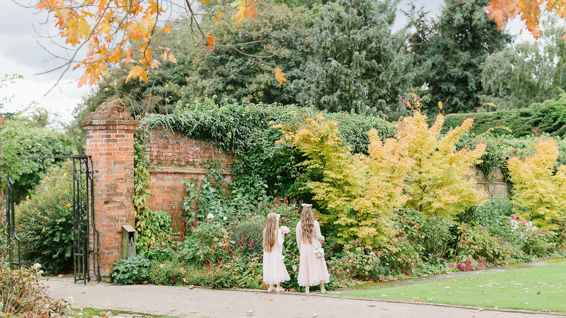 Flowers girls walk down the outdoor wedding aisle during a beautiful autumn wedding day