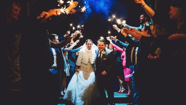 A happy couple are congratulated with sparklers at night - winter wedding ideas