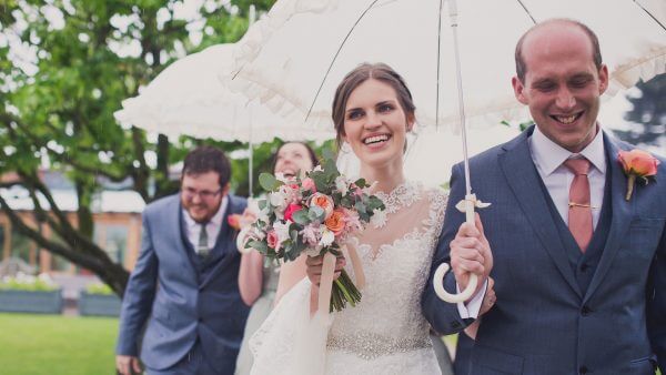 A bride carries a vintage wedding umbrella with gorgeous spring wedding flowers - pink flowers