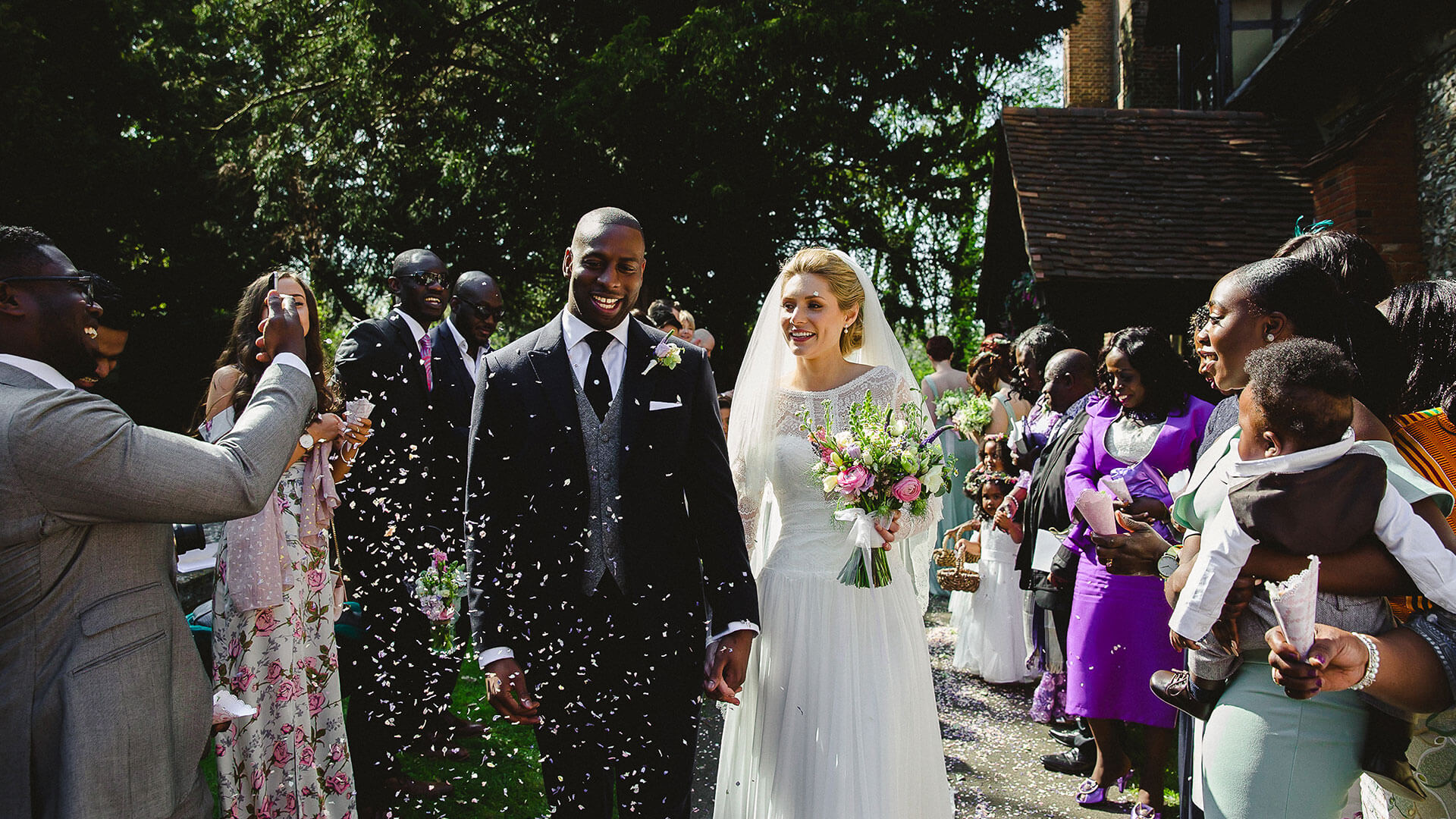 Guests throw confetti at a happy couple after their church wedding in Essex